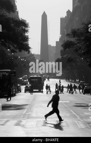 L'uomo attraversando Roque Sáenz Peña Ave., a miday. Obelisco (obelisco) monumento a sfondo. Foto Stock