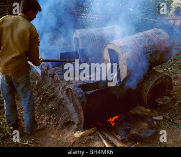 Lavoro giovane uomo tarmac di riscaldamento per lavori stradali Junger Mann sterzata erhitzt für den Strassenbau Mrauk-U MYANMAR Birmania Foto Stock