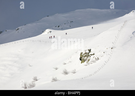 Cinque escursionisti con racchette da neve a piedi in un innevato paesaggio Auvergne. Cinq promeneurs en raquettes se déplaçant dans un paysage d'Auvergne Foto Stock