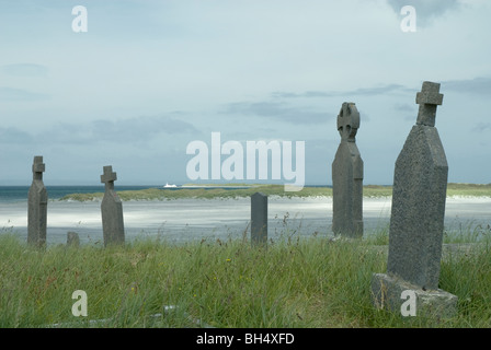 Lapidi che si affaccia sulla spiaggia, sul mare e un faro, Inis Mor, Isole Aran, Repubblica di Irlanda Foto Stock