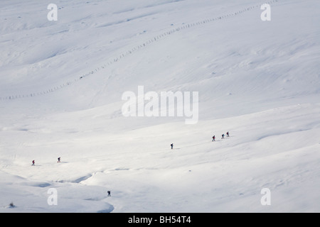 Un gruppo di escursionisti con racchette da neve a piedi in linea in inverno (Auvergne-France). Groupe de randonneurs se déplaçant en raquettes l'hiver. Foto Stock