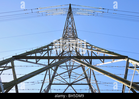 Elettricità pilone vista verso l'alto da un insolito angolo alla base con cielo blu chiaro dietro Foto Stock