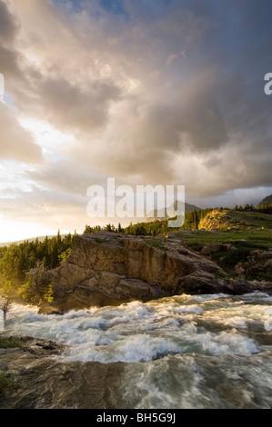 Swiftcurrent Creek cascades attraverso gorge inondate di luce di sunrise Foto Stock