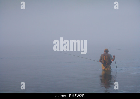 FLY FISHERMAN guadare in fiume con canna da mosca pesante velatura cattivo tempo Foto Stock