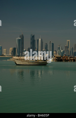 Visualizzazione verticale di Doha, Qatar skyline con mare in primo piano e dhow barche da pesca. Foto Stock