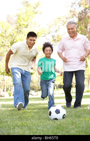 Nonno con figlio e nipote a giocare a calcio in posizione di parcheggio Foto Stock