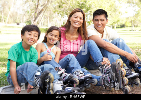 Famiglia mettendo su con pattini in linea in posizione di parcheggio Foto Stock