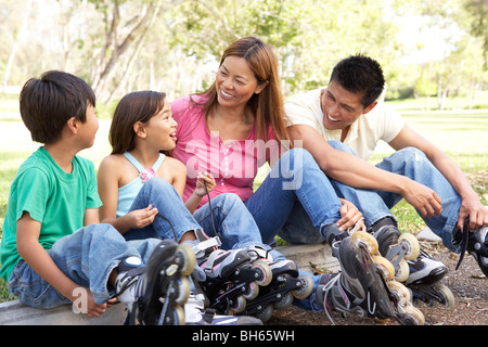 Famiglia mettendo su con pattini in linea in posizione di parcheggio Foto Stock
