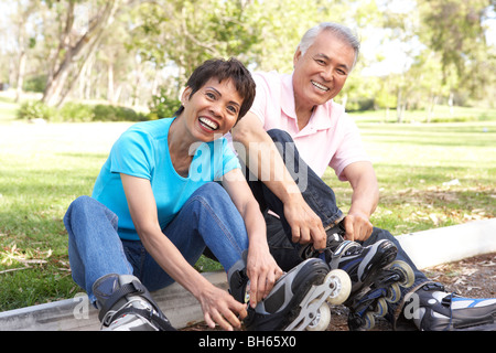 Coppia senior mettendo su con pattini in linea in posizione di parcheggio Foto Stock