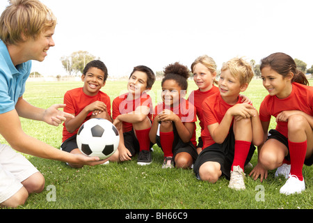 I ragazzi e le ragazze nella squadra di calcio con pullman Foto Stock