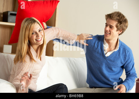 Coppia giovane avente giocare lotta sul divano Foto Stock