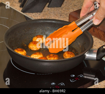 Freschi saltati funghi prataioli essendo servito con le pinze da padella Foto Stock