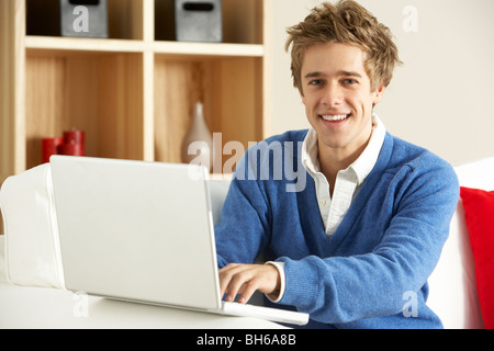 Giovane uomo utilizzando portatile a casa Foto Stock