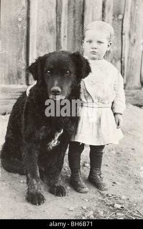 Bambina custodito da enorme cane nero Foto Stock