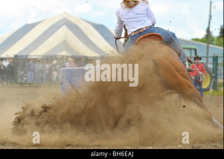 Un concorrente rodeo competere in un Barrel racing evento sotto arena polverose condizioni. Foto Stock