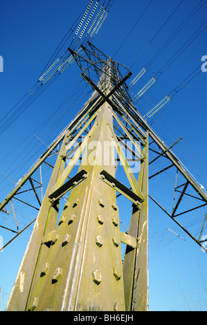 Elettricità pilone vista verso l'alto da un insolito angolo alla base di un supporto con cielo blu chiaro dietro Foto Stock