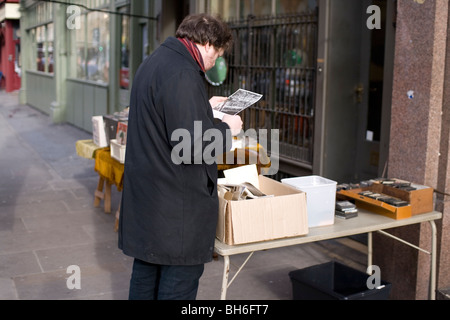 Un uomo esamina un pezzo di ephemera in una fase di stallo a Londra il Commercial St, E1 Foto Stock
