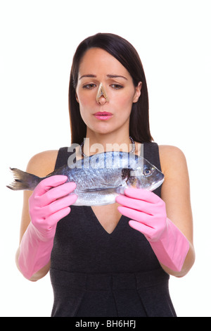 Una donna che indossa guanti di gomma tenendo un pesce crudo, isolato su sfondo bianco Foto Stock