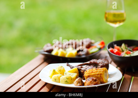 La grigliatura a summer weekend. Carni grigliate di carne e verdure servita all'esterno. Foto Stock