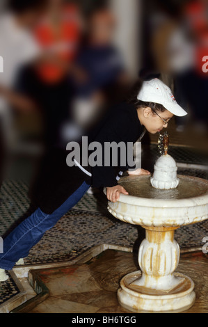 Meknes, Marocco. Scolaro bevande dalla fontana al Mausoleo di Moulay Ismail. Foto Stock
