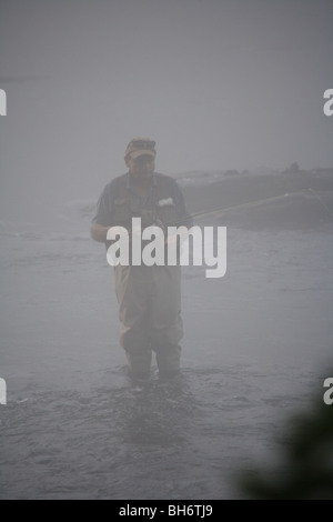 Pescatore a mosca la pesca in fiume con canna da mosca pesante velatura cattivo tempo Foto Stock