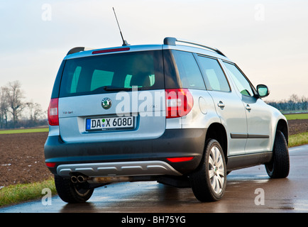 Posteriore, vista laterale Skoda Yeti SUV, 2010 modello in luce blu metallizzato parcheggiata su una strada vicino a un campo Foto Stock