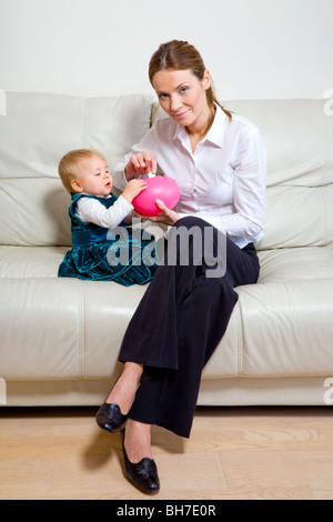 Madre con il suo bambino adorabili e un salvadanaio Foto Stock