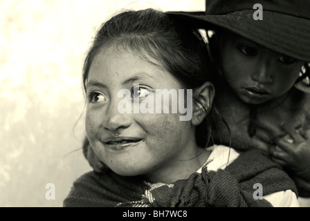 Ecuador, Latacunga, close-up di una ragazza che guarda lontano e sorridente, il suo bambino gemelli in background Foto Stock