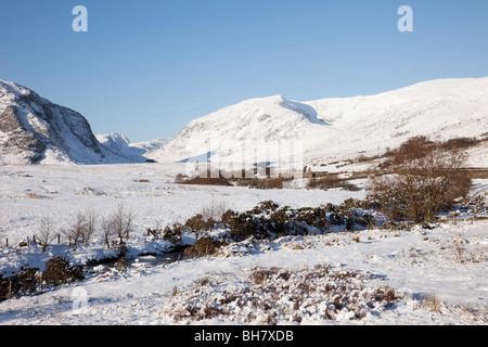 Valle Ogwen, Conwy, Galles del Nord, Regno Unito. Afon Llugwy River nel paesaggio invernale con la neve sulle montagne del Parco Nazionale di Snowdonia. Foto Stock