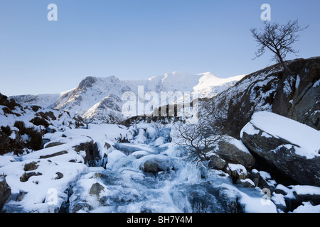 Cascata ghiacciata con Y Garn al di là della montagna nel Parco Nazionale di Snowdonia in inverno. Ogwen, Gwynedd, il Galles del Nord, Regno Unito, Gran Bretagna Foto Stock