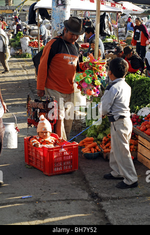 Ecuador, Saquisili, ragazzo giocando al traino di sua sorella bambino seduto in un rosso cassa in plastica Foto Stock