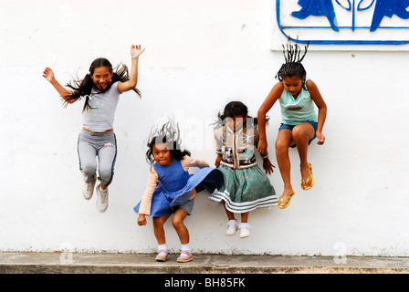 Ecuador, Yuarmachoa, gruppo di ragazze ecuadoriane da costa e anche da tribù indigene jumping davanti ad un muro bianco Foto Stock