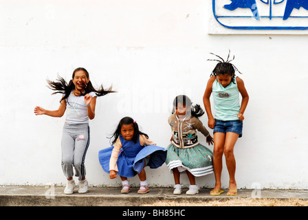 Ecuador, Yuarmachoa, gruppo di ragazze ecuadoriane da costa e anche da tribù indigene jumping davanti ad un muro bianco Foto Stock