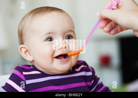 Baby sitting in poltrona essendo alimentato Foto Stock