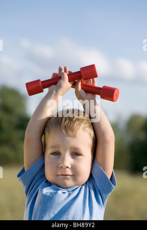 Un ragazzo di contenimento dei pesi a mano sopra la sua testa Foto Stock