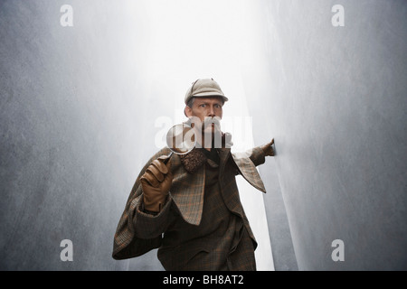 Un uomo vestito come Sherlock Holmes in possesso di una lente di ingrandimento Foto Stock