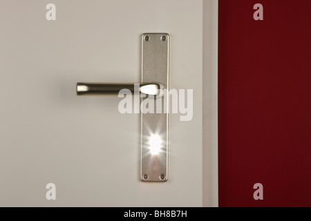 Dettaglio di una luce che risplende attraverso il buco della serratura di una porta Foto Stock