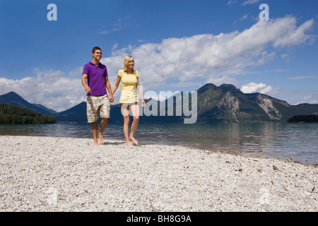 Una giovane coppia facendo una passeggiata da un lago Foto Stock