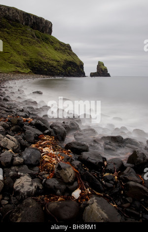 Una lunga esposizione delle onde che si infrangono sulla spiaggia rocciosa ai piedi delle scogliere di Talisker Bay, Skye, Scozia Foto Stock