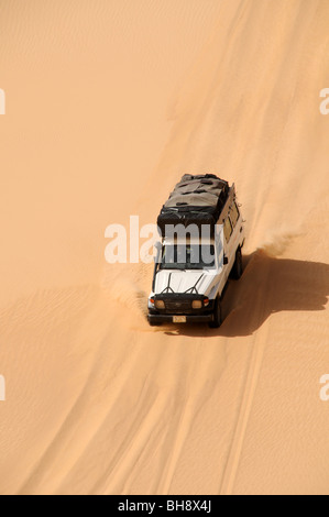 Un safari nel deserto land cruiser jeep 4x4 di creste una gigantesca duna di sabbia nel grande mare di sabbia del deserto occidentale, Sahara egiziano, Egitto. Foto Stock