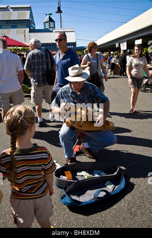 L'uomo musicista di strada, riproduzione di organetto di barberia strumento a corda con il bambino a guardare al mercato degli agricoltori, Bellingham, Washington, Stati Uniti d'America Foto Stock