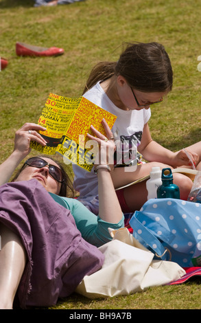 Donna e bambino la lettura di libri che giace sull'erba al di fuori di relax sotto il sole a Hay Festival 2009. Foto Stock