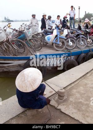 Il Vietnam il caricamento di scooter e biciclette di una chiatta per attraversare il fiume a Hoi An Foto © Julio Etchart Foto Stock