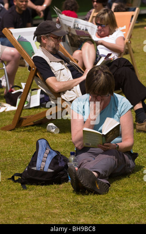 La gente la lettura e il relax sat su erba e in sedie a sdraio fuori nel sole a Hay Festival 2009. Foto Stock