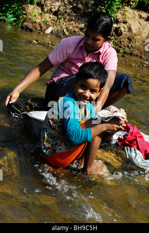 Karen bambini rifugiati a lavare i panni nel fiume, Tailandese confine birmano, Tak, nel nord della Thailandia. Foto Stock