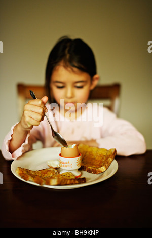 Bambina di cinque anni mangia uova sode per la colazione Foto Stock