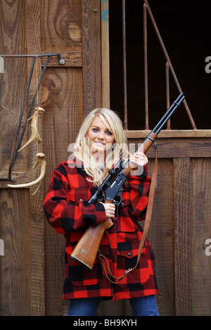 Giovane donna 21 Y.O. Il cacciatore femmina HOLDING MARLIN 30-30 fucile calibro nella parte anteriore del granaio Foto Stock