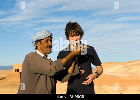 Il serpente incantatore con un turista nei pressi di Ait Benhaddou, Marocco. Foto Stock