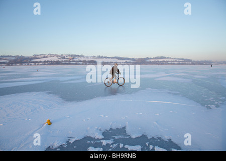 Un uomo in bicicletta su un castello di congelati Semple Loch, a Lochwinnoch nel Renfrewshire, Scotland, Regno Unito Foto Stock