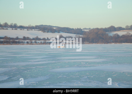 Cani da passeggio uomo su un castello congelato Semple Loch in inverno, Clyde Muirshiel Regional Park, Lochwinnoch, Renfrewshire, Scozia, Regno Unito Foto Stock